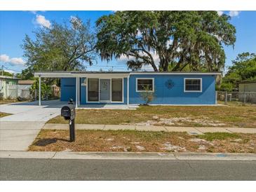 Charming single-story blue home featuring a covered carport and well-maintained landscaping at 451 Hibiscus Rd, Casselberry, FL 32707