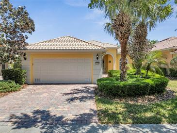Charming home featuring a paver driveway, a two-car garage, manicured landscaping, and a barrel tile roof at 11763 Eagle Ray Ln, Orlando, FL 32827