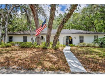Charming white home with an American flag, trees, and lush landscaping at 1304 Deer Run Dr, Winter Springs, FL 32708