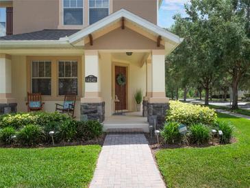 Inviting covered front porch with stone accents, rocking chairs, and well-manicured landscaping at 14242 Avenue Of The Groves, Winter Garden, FL 34787