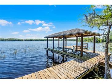 Waterfront home features a private boat dock with a boat lift on a sunny day at 16692 Lake Pickett Rd, Orlando, FL 32820