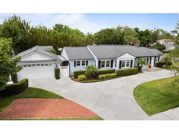 Charming home with a well-manicured lawn, complemented by a long driveway and lush landscaping at 1702 N Westmoreland Dr, Orlando, FL 32804