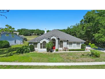 Charming single-story home with a well-manicured lawn, red door, and tasteful landscaping at 1851 Sweetwater West Cir, Apopka, FL 32712
