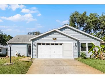 Charming single-story home featuring a well-maintained lawn, attached two-car garage and light-blue siding at 32537 Oak Park Dr, Leesburg, FL 34748