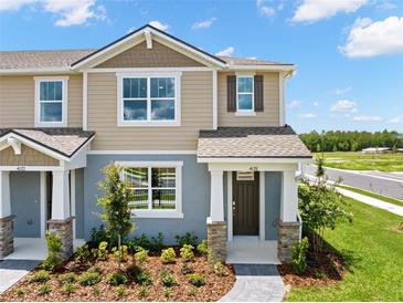 Inviting two-story townhome with stone accents, landscaped yard, and covered porch at 4216 Sadler Rd, Apopka, FL 32712