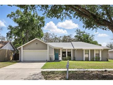 Well-kept single-story house featuring a two-car garage, blue front door, and tidy landscaping at 5163 Lighthouse Rd, Orlando, FL 32808