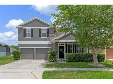 Charming two-story gray home featuring a two-car garage, lush landscaping, and a welcoming front entrance at 10435 Eastpark Lake Dr, Orlando, FL 32832