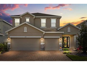Charming two-story home with a brick driveway and a well-manicured lawn at sunset at 1109 Castlevecchio Loop, Orlando, FL 32825