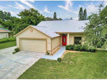 Charming single-story home with a well-manicured lawn, attached garage, and a bright red front door at 13245 Shore Dr, Winter Garden, FL 34787