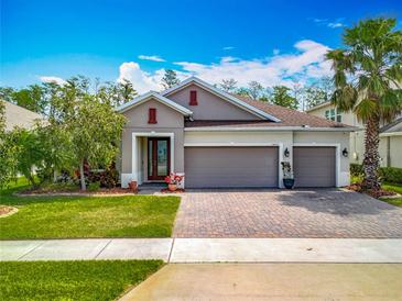 Charming single-story home with a three-car garage, beautiful landscaping, and a brick paver driveway at 14001 Jomatt Loop, Winter Garden, FL 34787