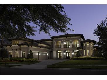 Stately two-story home featuring arched entryways, manicured landscaping, and a three-car garage at twilight at 14700 Avenue Of The Rushes, Winter Garden, FL 34787