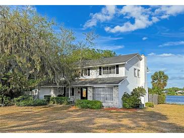 Charming two-story home with a brick facade and a well-maintained yard overlooking a serene lake at 240 Slade Dr, Longwood, FL 32750