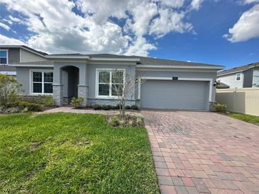 Charming single Gathering home with a brick driveway, two-car garage, and manicured lawn under a cloudy blue sky at 2741 Nottel Dr, St Cloud, FL 34772