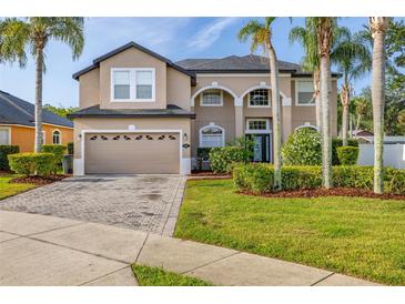 Elegant two-story home with mature landscaping, paver driveway, and a two-car garage under a blue sky at 305 Kays Landing Dr, Sanford, FL 32771