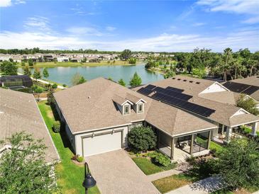 Stunning aerial view of a lakeside home featuring solar panels and a paver driveway, situated in a vibrant community at 459 Dancing Water Dr, Winter Springs, FL 32708
