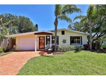 Charming single-story home featuring a well-manicured lawn, palm trees, and a cozy seating area on the front porch at 505 S Cooper St, New Smyrna Beach, FL 32169