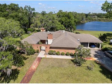 Aerial view of a single-story brick house with a covered carport and lake view at 29 Windsor Isle Dr, Longwood, FL 32779