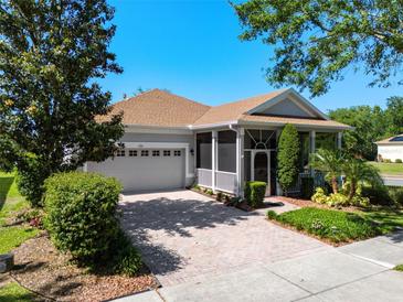 Charming single-story home with a screened porch, two-car garage, and a well-maintained brick driveway at 115 Crescent Moon Dr, Groveland, FL 34736