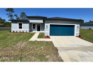 Charming single-story home featuring a modern design, blue garage door and well-manicured lawn at 15750 Sw 40Th Ter Sw 40Th Ter, Ocala, FL 34473