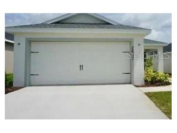 This home features a spacious two-car garage with carriage accents and a concrete driveway at 2607 Tulip Dr, Davenport, FL 33837