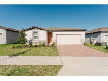 Charming single-story home featuring a brick driveway, two-car garage, and well-manicured lawn at 349 Guadlupe St, Haines City, FL 33844