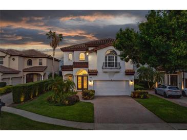 Stunning two-story home with well-manicured landscaping and a paver driveway at dusk at 8125 Via Rosa, Orlando, FL 32836