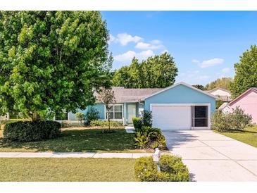 Charming single-Gathering home featuring a lush green lawn, mature trees, and a two-car garage at 13234 Moonflower Ct, Clermont, FL 34711
