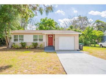 Charming single-story home featuring a red door, front yard, and attached one car garage at 1411 N Powers Dr, Orlando, FL 32818
