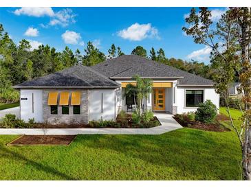 Inviting single-story home featuring white exterior, yellow front door, well-manicured lawn, and lush landscaping at 18026 Reynolds Pkwy, Orlando, FL 32833