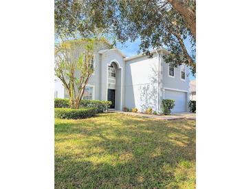 Charming two-story home with a manicured lawn, mature trees, and a light blue and white exterior paint scheme at 2131 Nicollett Way, Leesburg, FL 34748