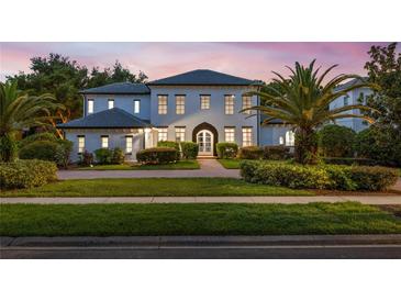 Stunning two-story home featuring lush landscaping, a symmetrical facade, and a welcoming arched entrance at 10849 Emerald Chase Dr, Orlando, FL 32836