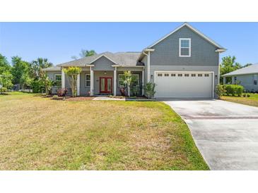 Charming two-story home with a well-manicured lawn, gray siding and a red front door at 1103 Lindley Cove Cir, Deland, FL 32724