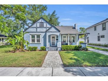 Charming light blue bungalow with a well-manicured lawn and a brick pathway leading to the front door at 1413 W Harvard St, Orlando, FL 32804