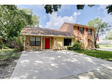 Charming two-story home with stone accents, a bright red front door, and a spacious driveway at 5518 Cretan Way, Winter Park, FL 32792