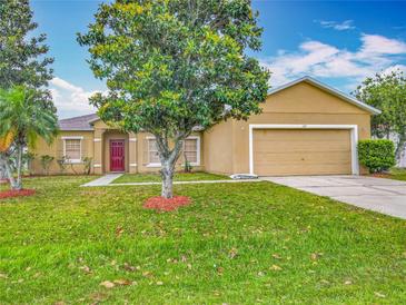 Charming single-story home with a well-maintained lawn, lush landscaping, and a vibrant red front door at 107 Carlisle Ct, Kissimmee, FL 34758
