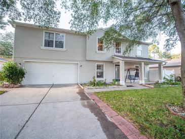 Two-story home with a manicured front yard, two-car garage, and a welcoming front porch with a swing at 1870 Vale Dr, Clermont, FL 34711