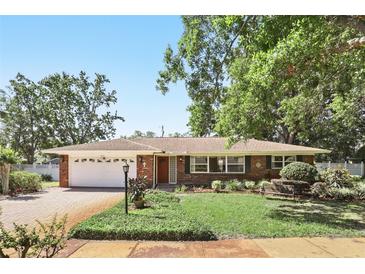 Charming brick home with a well-manicured lawn, lush landscaping, and a cozy bench, creating inviting curb appeal at 2024 Linden Road, Winter Park, FL 32792