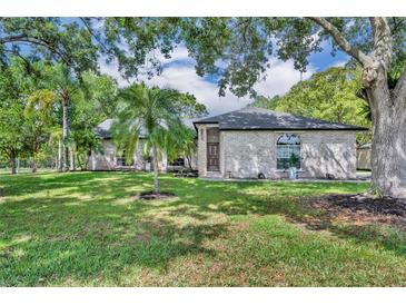 Charming single-story brick home with lush front yard and mature trees, offering a serene setting at 2810 Windsong Ln, St Cloud, FL 34772