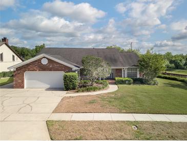 Charming brick home featuring a lush front yard, mature trees, and attached two-car garage at 3306 Fishermans Cv, Winter Park, FL 32792