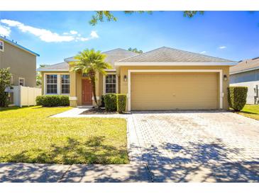 Inviting single-Gathering home with a manicured lawn, palm tree, and a brick-paved driveway at 3812 Creswick Cir, Orlando, FL 32829