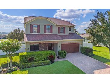Charming two-story home with a well-manicured lawn, brick-paved driveway and mature landscaping at 4113 Longbow Dr, Clermont, FL 34711