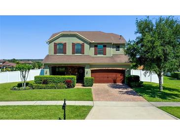 Charming two-story home featuring manicured landscaping, a brick driveway, and a two-car garage at 4113 Longbow Dr, Clermont, FL 34711
