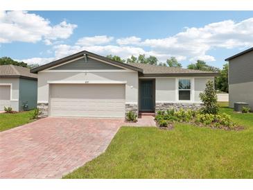 Charming single-story home featuring a brick driveway, attached garage and well manicured landscaping at 4717 Jasmine Cir, Leesburg, FL 34748