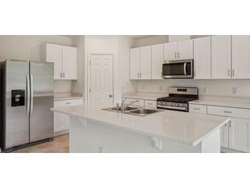 Bright kitchen features white cabinets, stainless steel appliances, a large island and quartz countertops at 4728 Jasmine Cir, Leesburg, FL 34748
