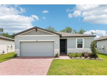 Charming one-story home with a two-car garage, brick driveway and a beautifully landscaped front yard at 4732 Jasmine Cir, Leesburg, FL 34748