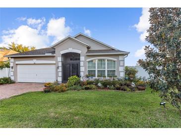 Charming single-story home featuring a manicured lawn and colorful flower beds under a blue sky at 600 Rob Roy Dr, Clermont, FL 34711