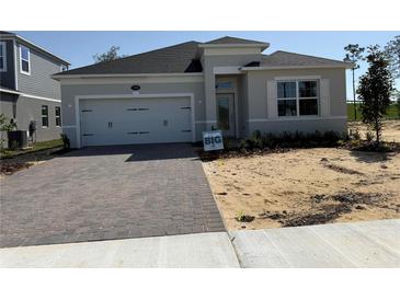 Charming single-story home with a two-car garage and brick paver driveway, showcasing modern design at 738 Pointe Emerson Blvd, Apopka, FL 32703