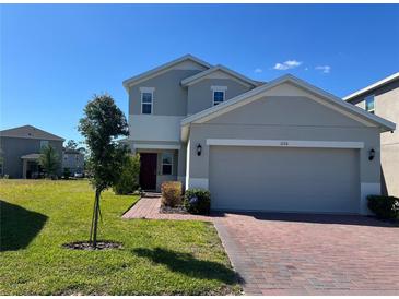Two-story home featuring a well-maintained lawn, brick driveway, and an attached two-car garage at 1116 Myrtle Hammock Ln, Davenport, FL 33837