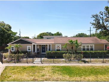 Charming single-story home featuring a manicured lawn, mature landscaping, and secure black metal fencing at 1122 Vassar St, Orlando, FL 32804