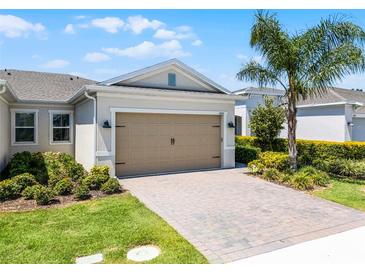 Home featuring a spacious garage, a paver driveway, and beautiful landscaping with a mature palm tree in the front yard at 2026 Key Bay Trl, Kissimmee, FL 34747